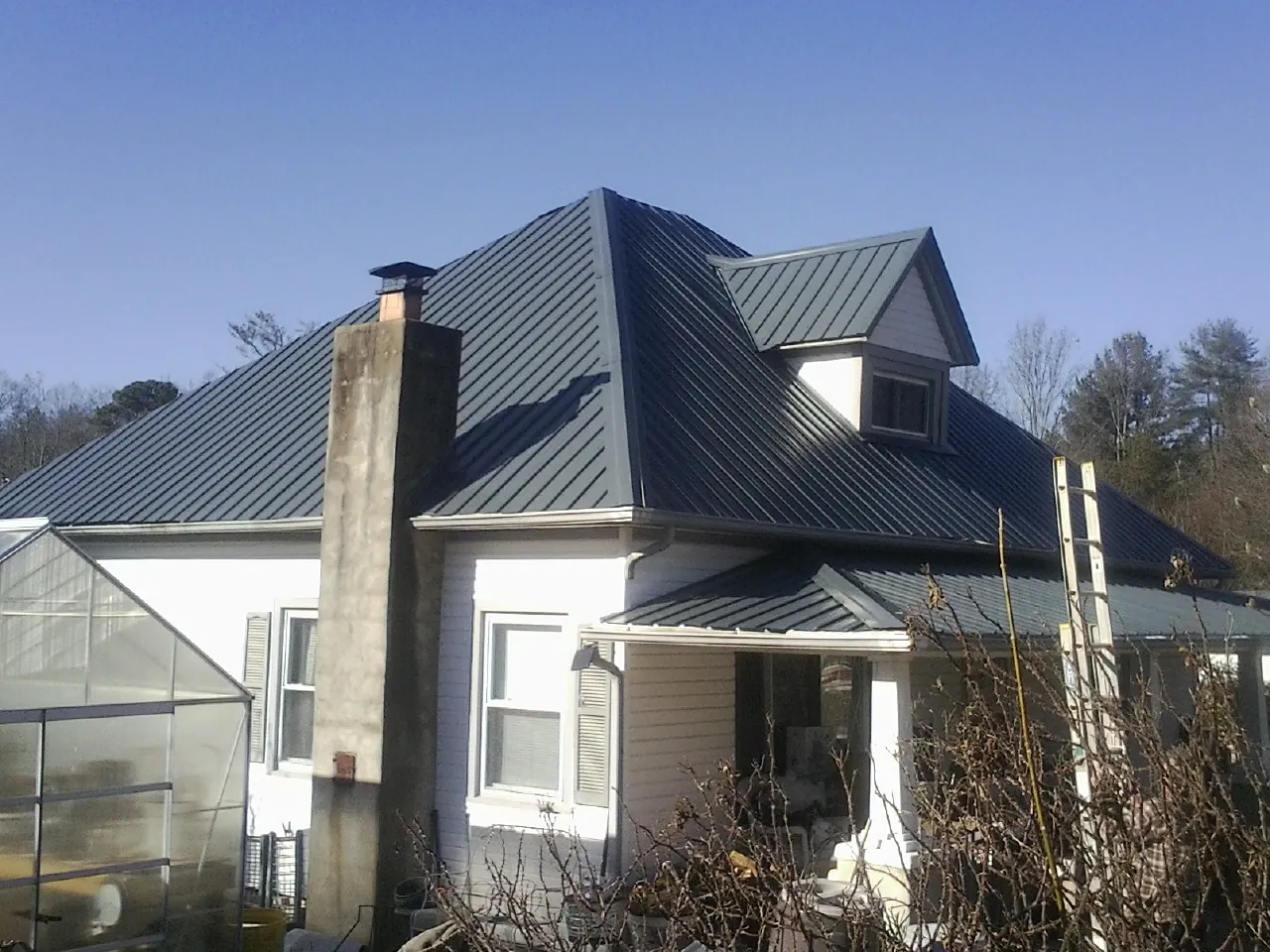 Dark blue standing seam metal roof on a white farmhouse with dormer — Slate & Tile Roof Repair by Roofing Brothers in Brodheadsville