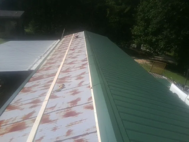 Old rusted panels beside newly installed green metal roofing — Wind Damage Roof Repair by Roofing Brothers in Brodheadsville