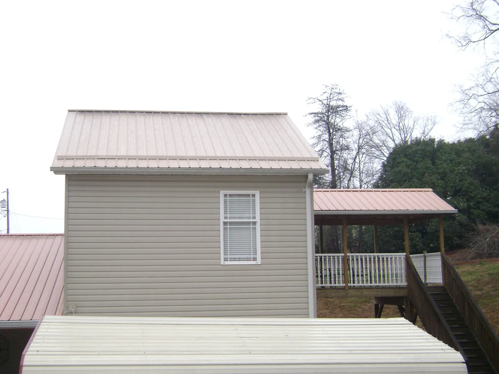 Tan metal roofs on a two story addition and attached porch, from a Roof Replacement job in Brodheadsville