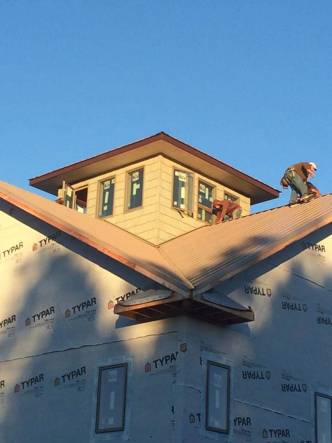 Roofers working around a rooftop cupola on a new metal roof at sunset — Roof Waterproofing in Brodheadsville by Roofing Brothers